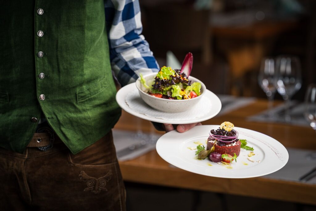 Service bringt Salat und Tatar an den Tisch